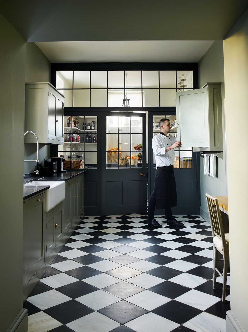 Chef Daniel in the large kitchen where units by Plain English complement a long wooden table and chairs.