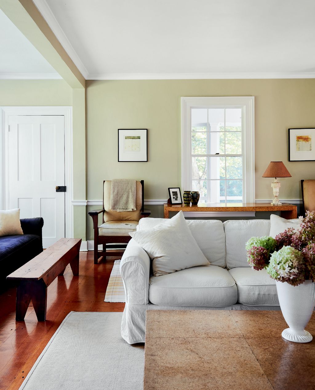 Image may contain Living Room Room Indoors Flooring Furniture Couch Wood Hardwood Interior Design Table and Flower