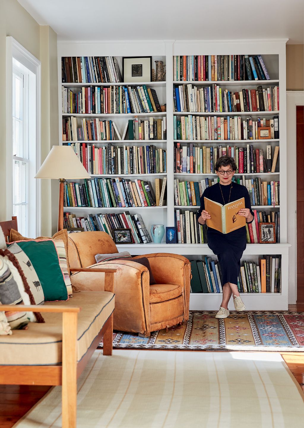 Image may contain Furniture Human Person Bookcase Couch Living Room Room Indoors and Shelf