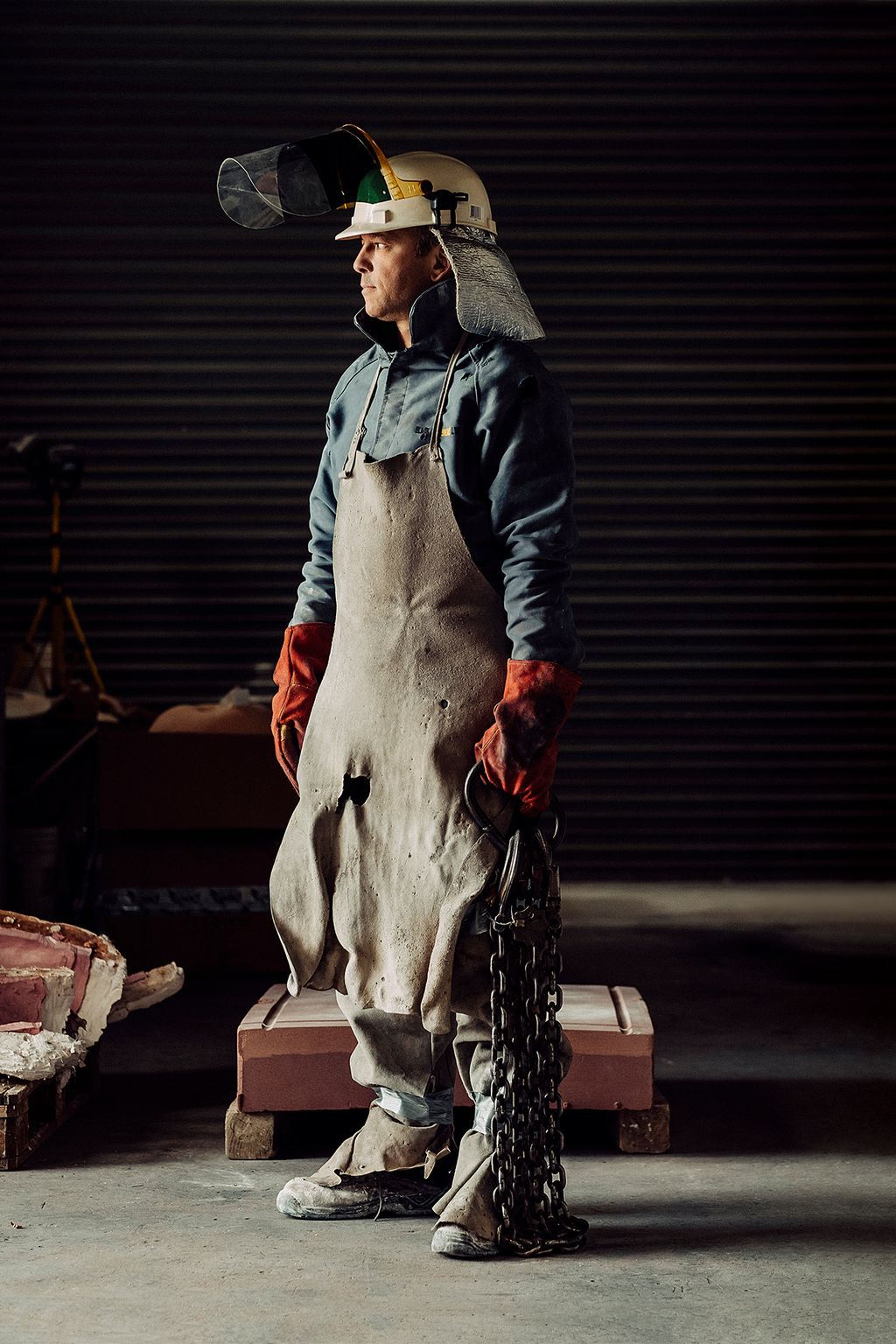 Farquhar in his foundry in Nairn wearing metal splash protective equipment with a lifting chain.