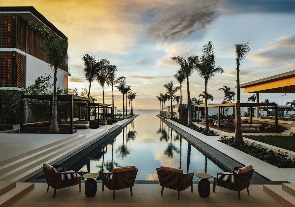 Image may contain Building Resort Hotel Water Palm Tree Arecaceae Tree Plant Wood Summer Waterfront and Boardwalk