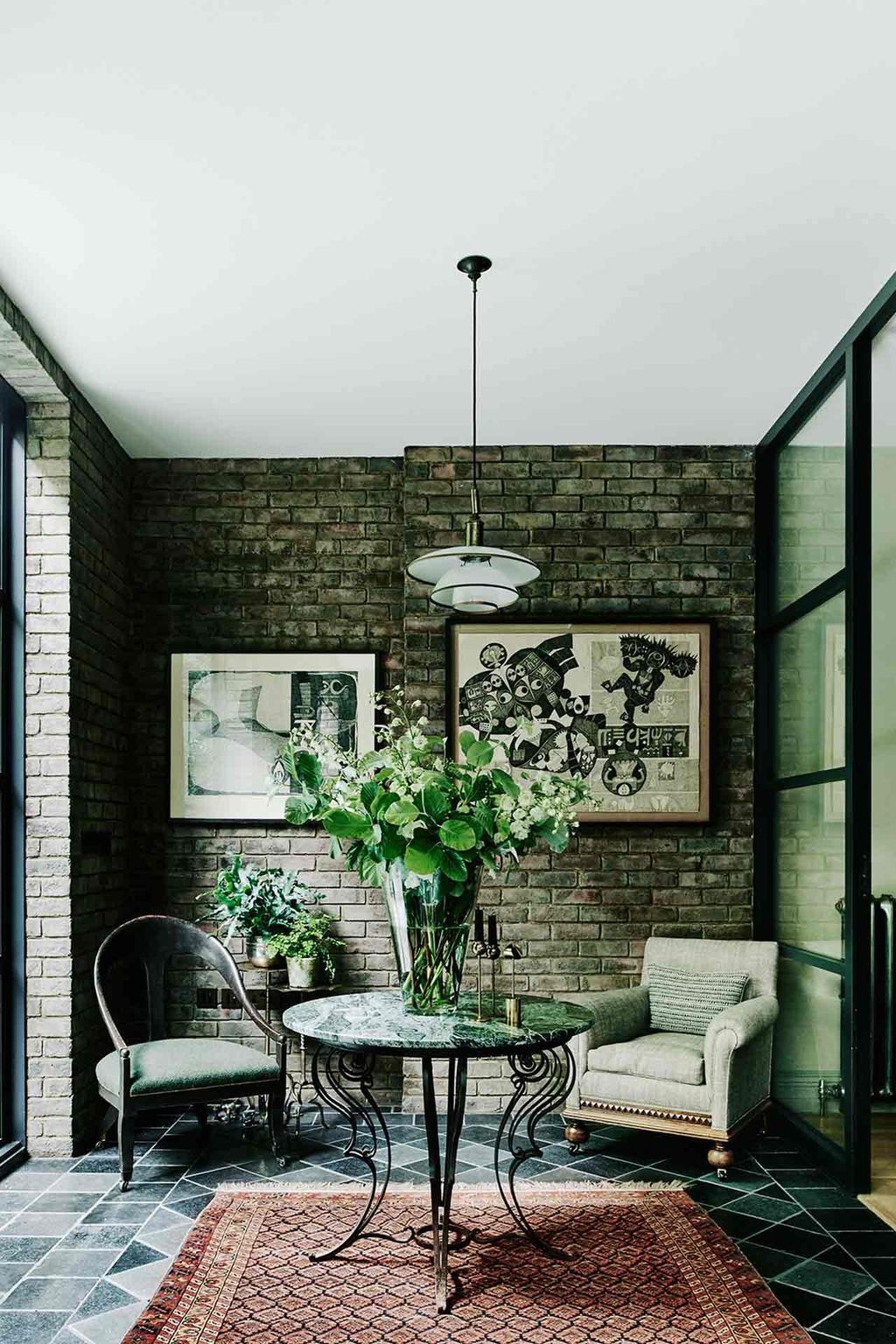 One end of the garden room on the lower ground floor has a Persian Qashqai rug with one of a pair of lights by the...