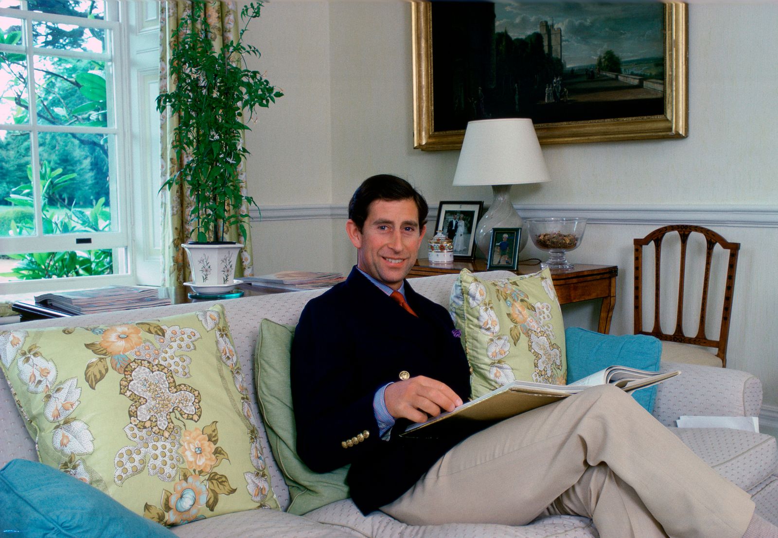 Image may contain Charles Prince of Wales Furniture Couch Lamp Table Lamp Home Decor Human Person and Cushion