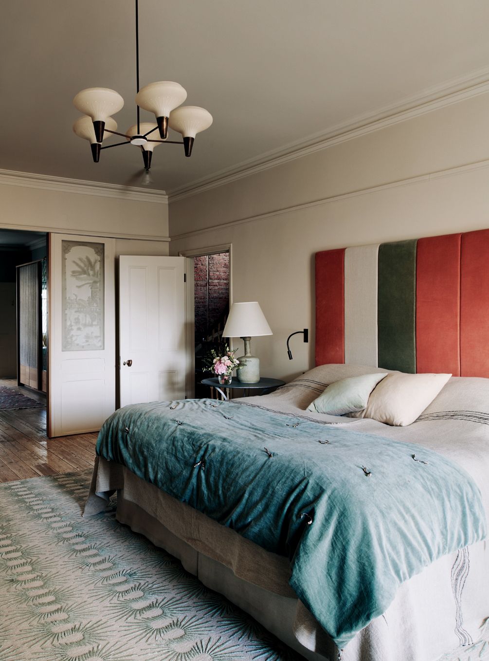 The headboard is made from handdyed velvet panels. A Sixties ceiling pendant hangs above Neisha Croslands ‘Hedgehog Sea...