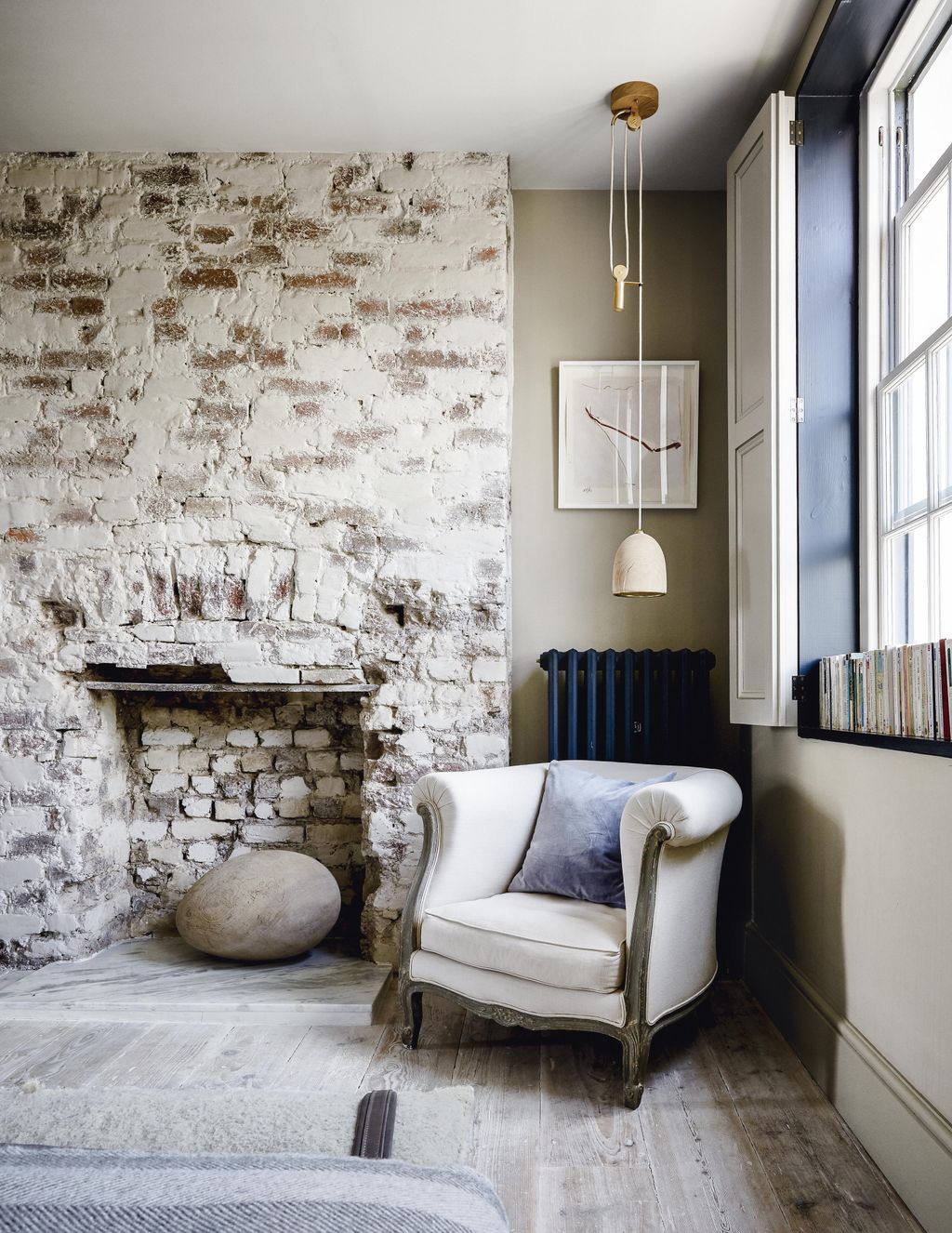 A ‘Surya greenoak pendant by Ochre hangs above a vintage French armchair in the main bedroom putty was used to whiten...