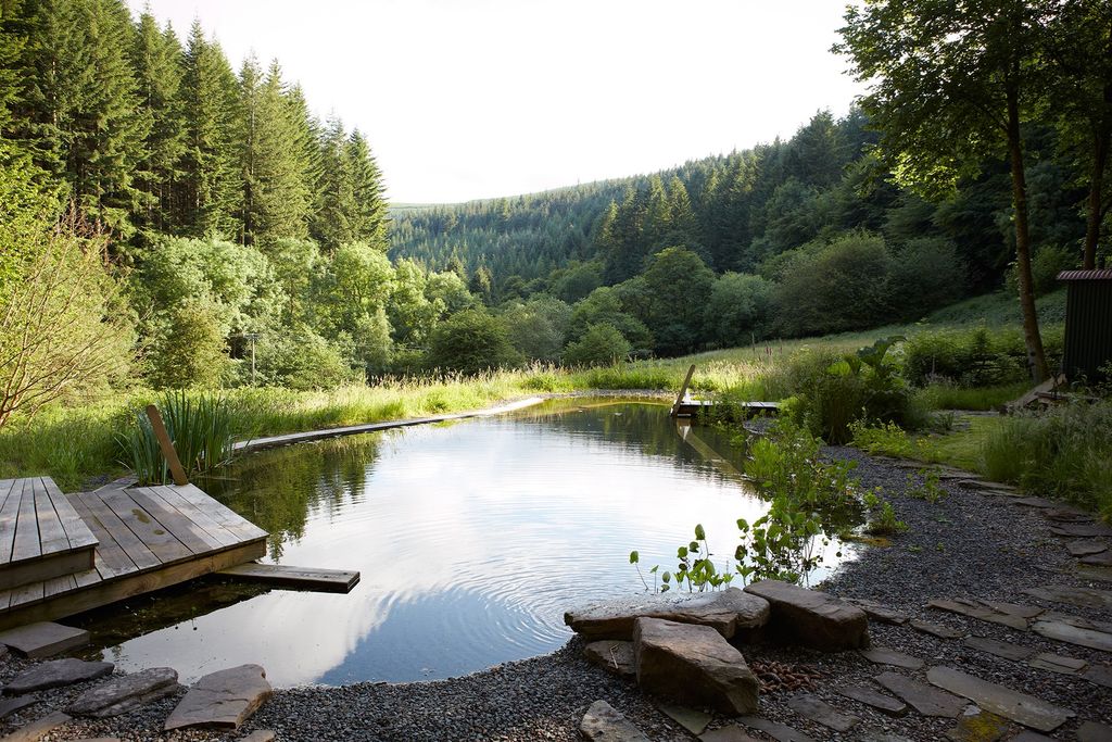A natural swimming pond forms the centerpiece of the gardens with views down the valley. A fringe of flag iris...
