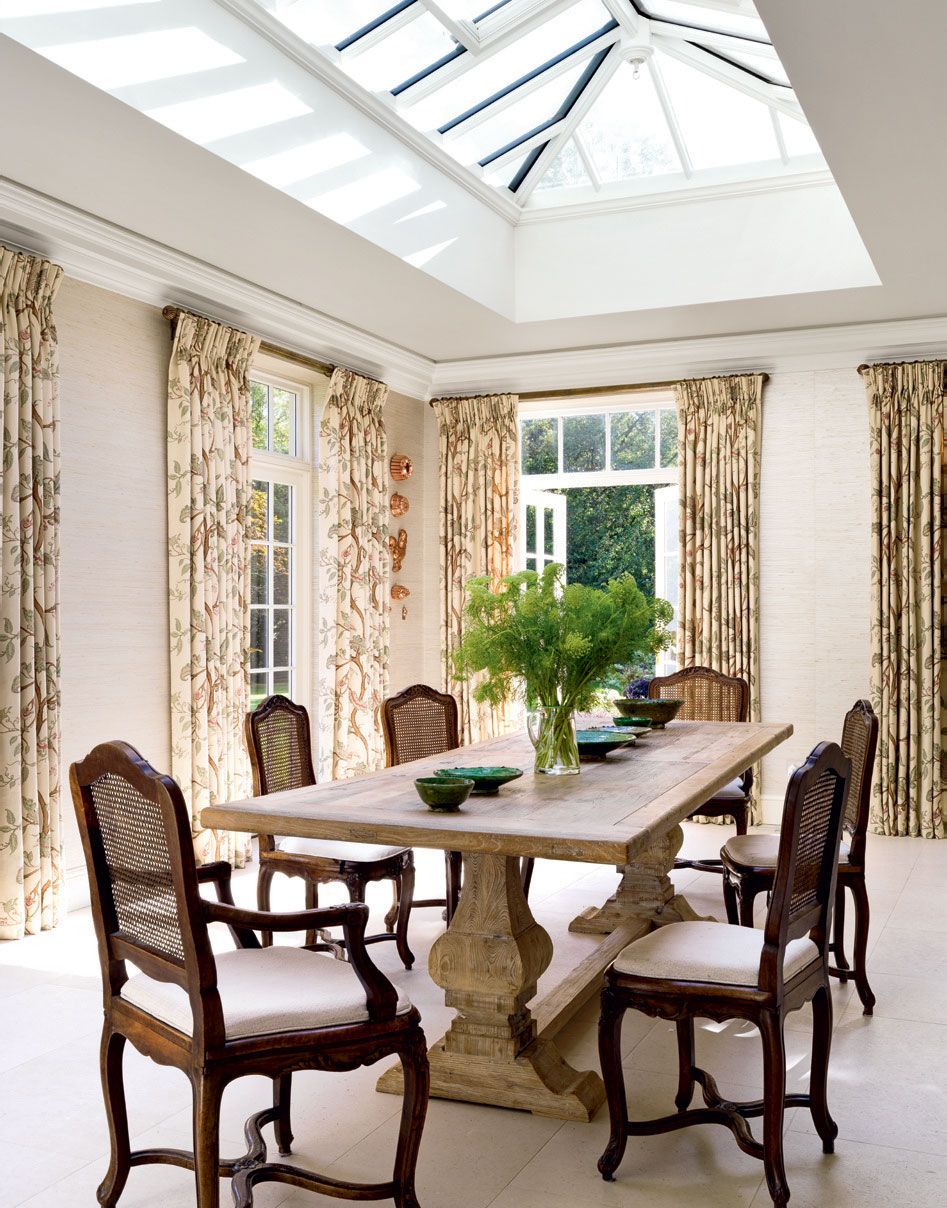 Beyond the marbletopped counter a dining table occupies the lightfilled space beside a run of french windows with...