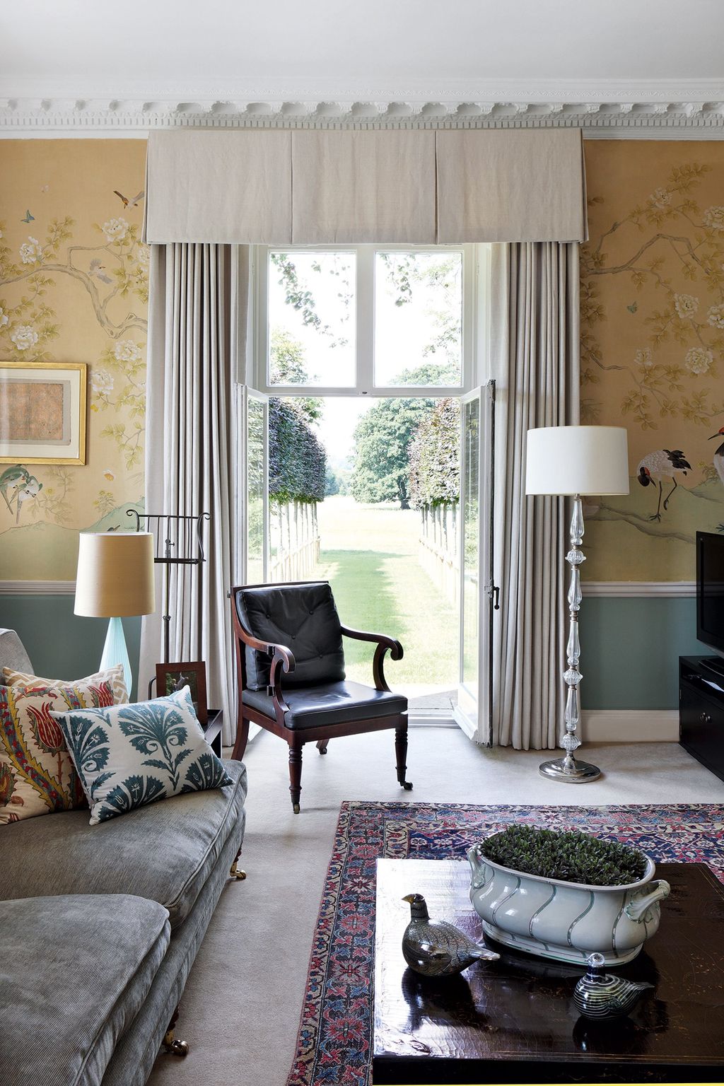 French windows open onto the garden from the sitting room which is decorated in an early handpainted de Gournay wallpaper.