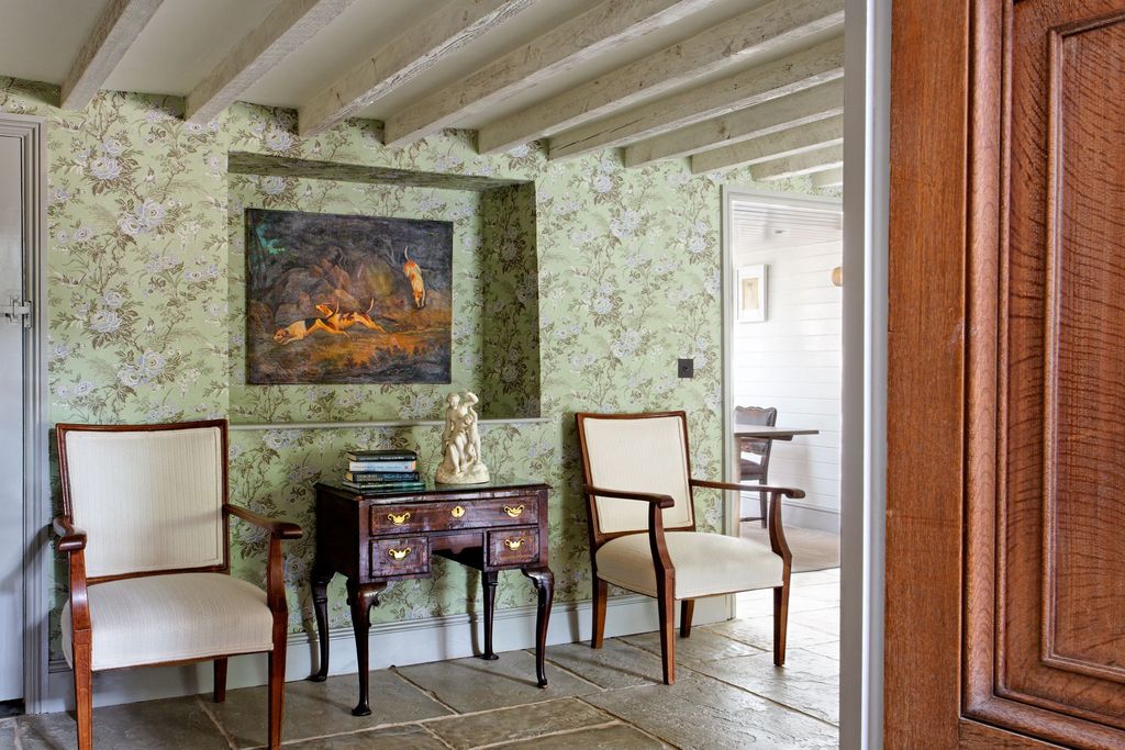 A pair of Forties chairs flanks an eighteenthcentury lowboy a seventeethcentury hunting picture a junkshop find hangs...
