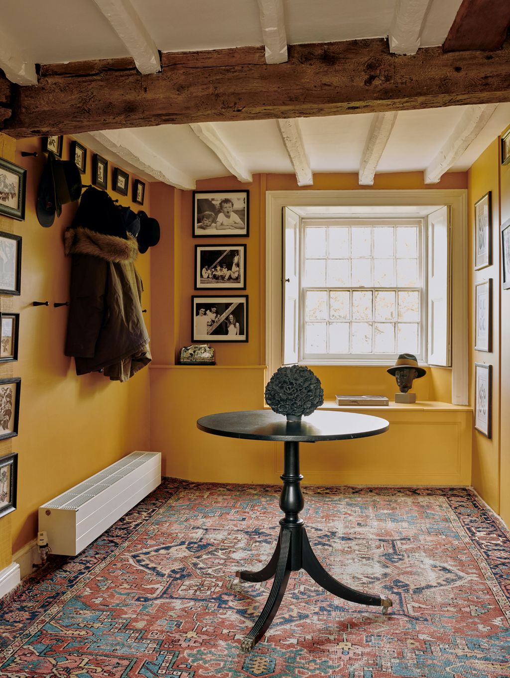 Walls painted in rich ‘India Yellow by Farrow Ball and an antique rug create a warm first impression.