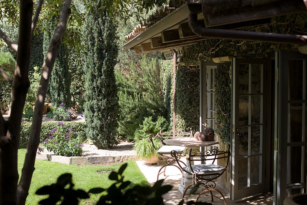 A table and chairs are arranged on a sunny terrace in the atrium.