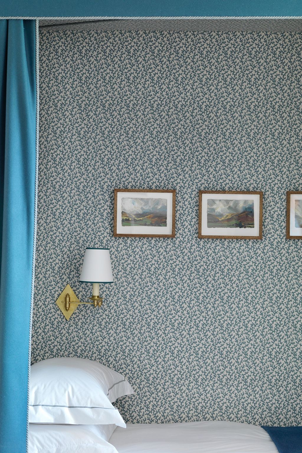 A light fixture and framed photographs along the wall make this four poster nook even more cozy than it already is.