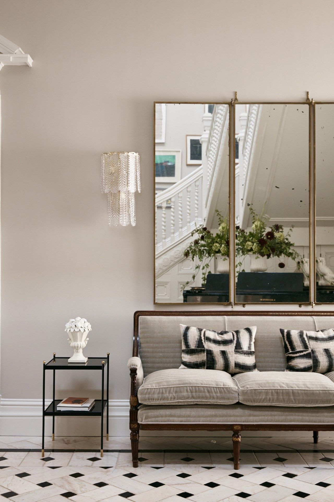 Seating in the hallway breaks up the large space and adds a little warmth with soft furnishings. An antique mirror hangs...