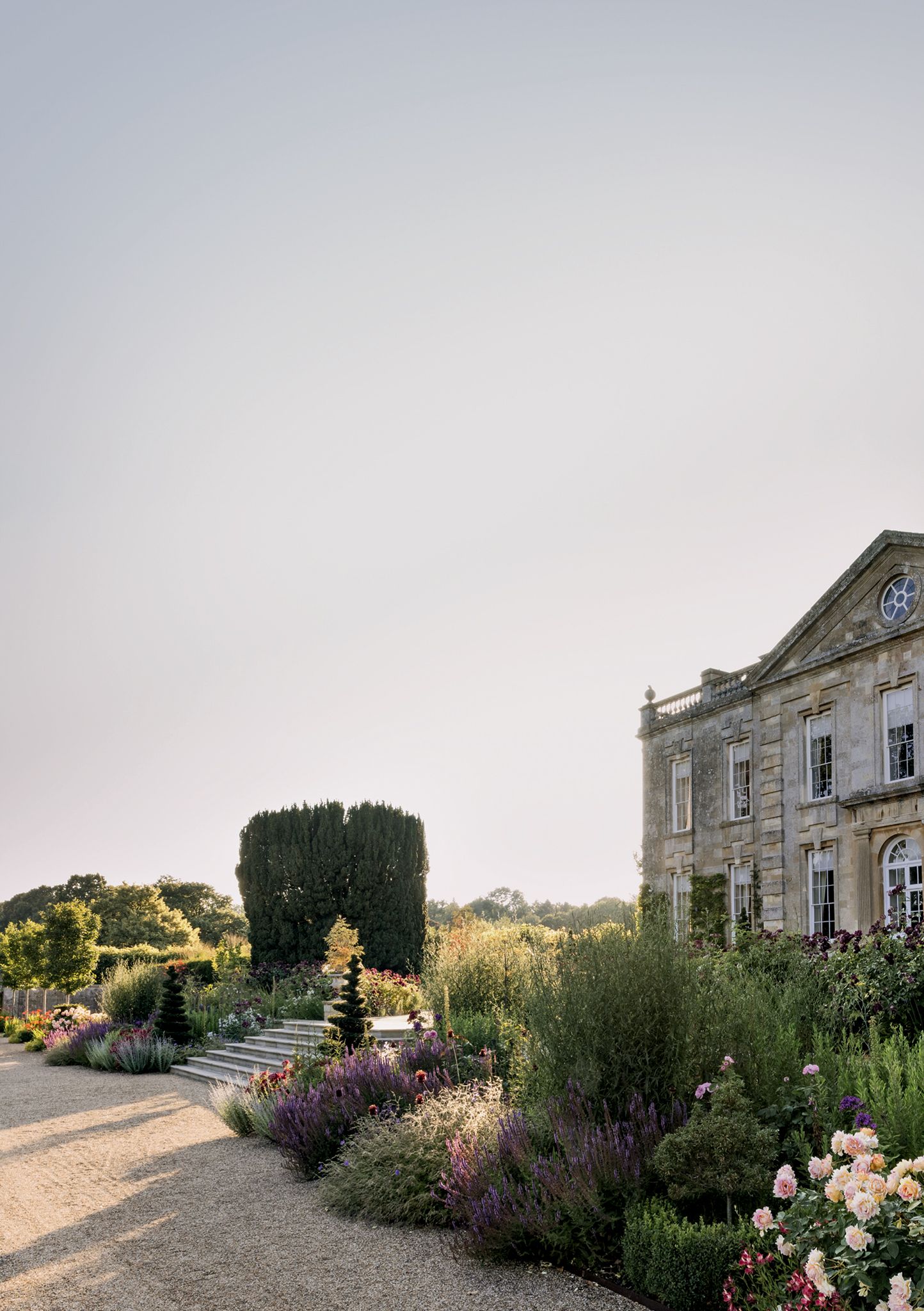 Steps descend from the front terrace through borders of mixed perennials and apricot Rosa ‘Rose des Cisterciens