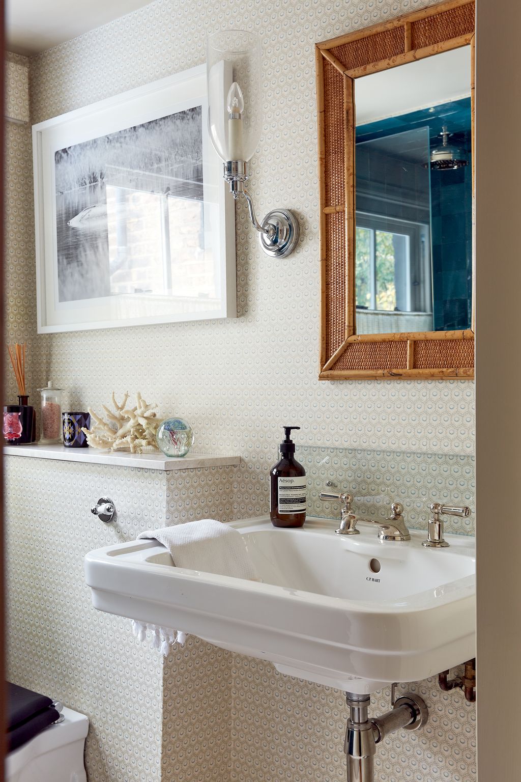 The bathroom on the landing is papered in GPJ Baker's 'Hawkbury' pattern while the glass wall lights are from Vaughan...