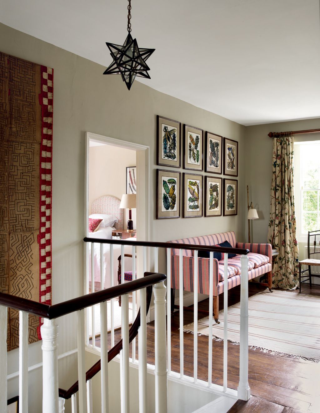 On the landing reproduction prints by EA Sguy part of a series from c1928 hang above an antique French sofa with its...