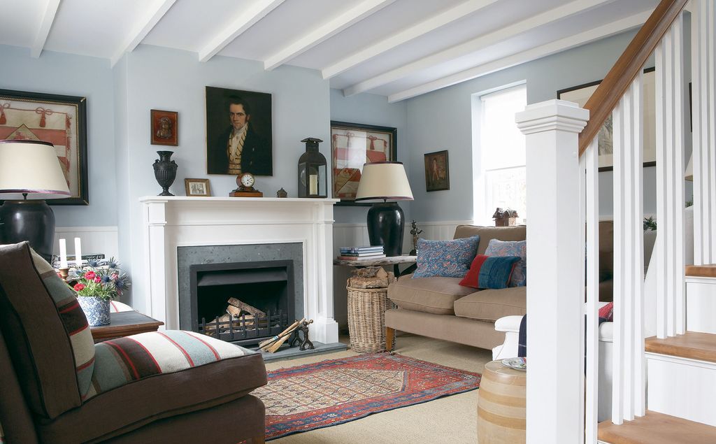 The sitting room is partially separated from the hall by the stairs. In frames either side of the fire are old trumpet...