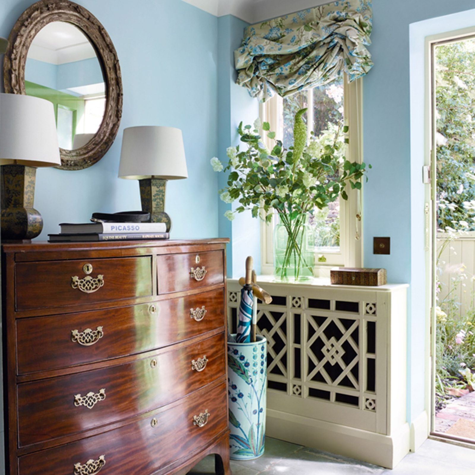 The blue entrance hall has flagstone floors and a very smart radiator cover. The Georgian mahogany chest of drawers was...