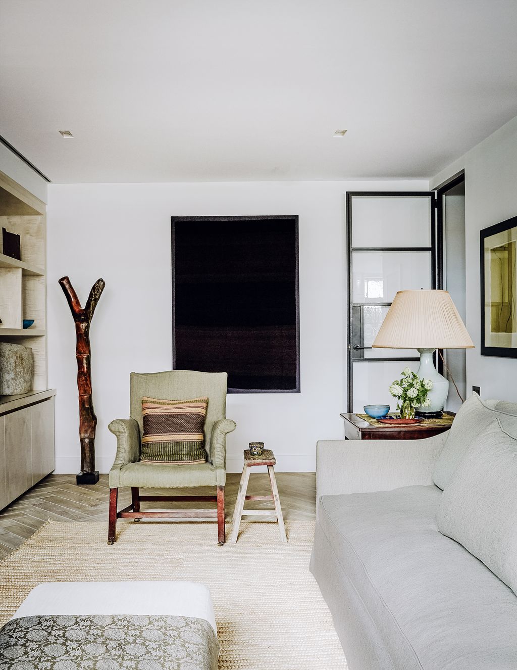 A forked wooden ladder by the Dogon people of Mali and a dark antique Aymara wool textile from Bolivia provide a...