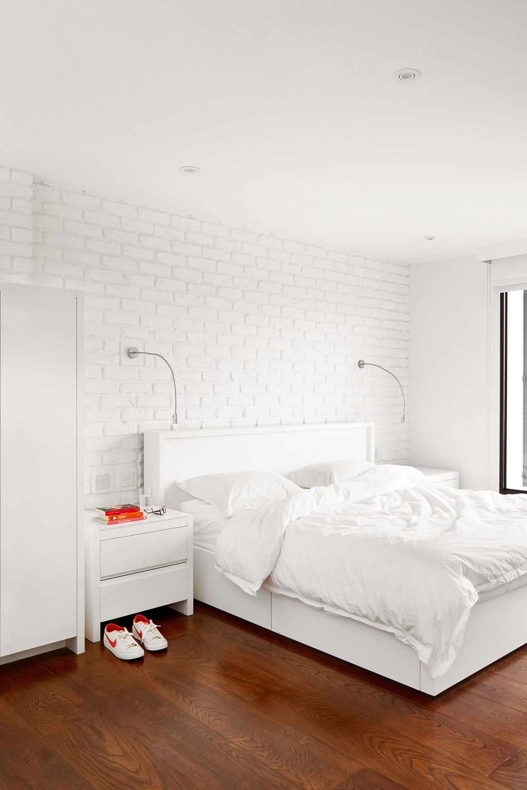 Oiled oak floorboards add warmth to the allwhite main bedroom.