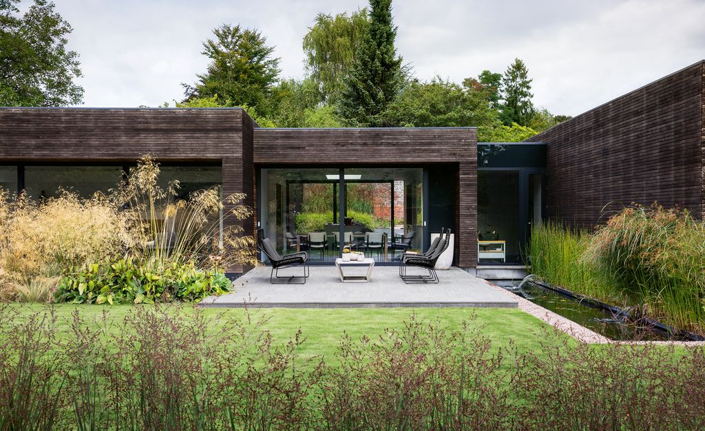 The dining room of the cedarclad house looks out on to a seating area on the basalt terrace. Grasses here include Stipa...