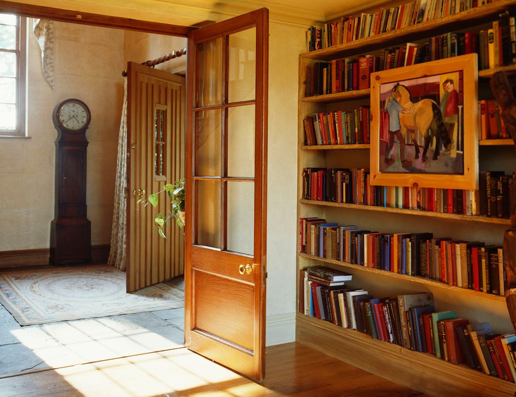 Image may contain Furniture Bookcase Wood Flooring Human Person Hardwood Floor Interior Design Indoors and Shelf