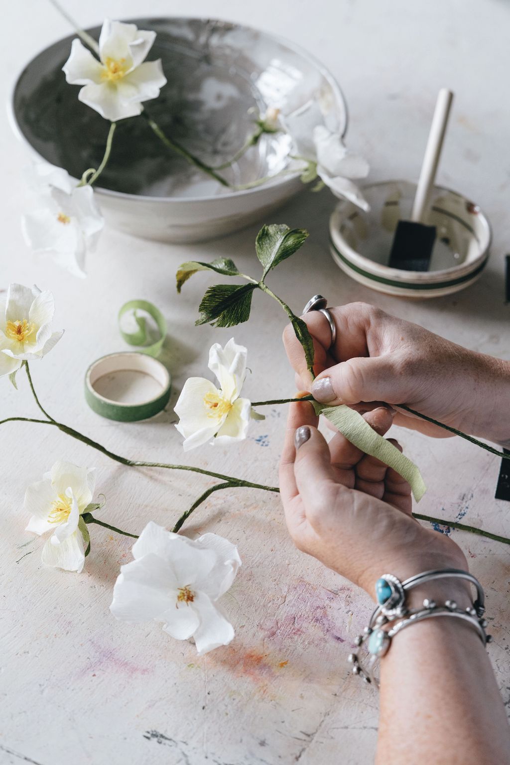 13.  Cut ribbons of green crepe and glue them around the stem from top to bottom.  14. Attach more flowers and leaves...