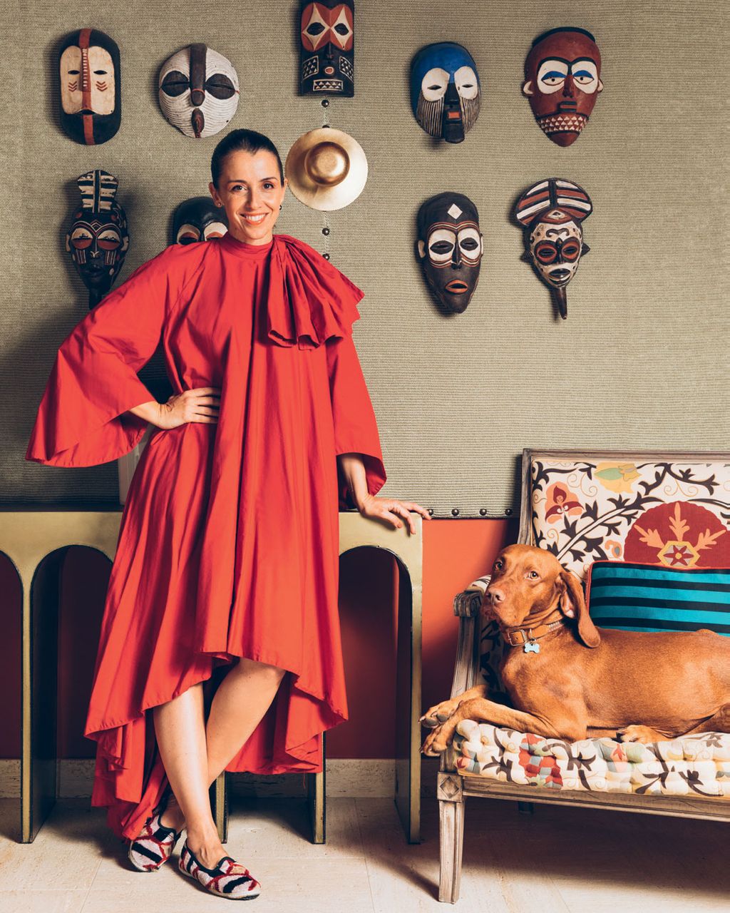 Gracinha and her Vizsla Zov in the second sitting room in front of a collection of masks found at a market in Angola...