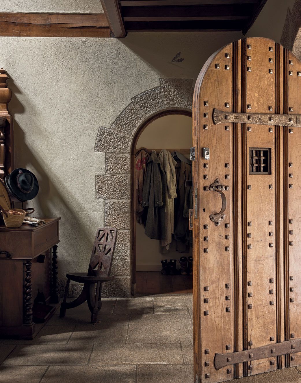An imposing studded oak front door is echoed by graniteframed arched doorframes in this Dartmoor house revived by Retrouvius