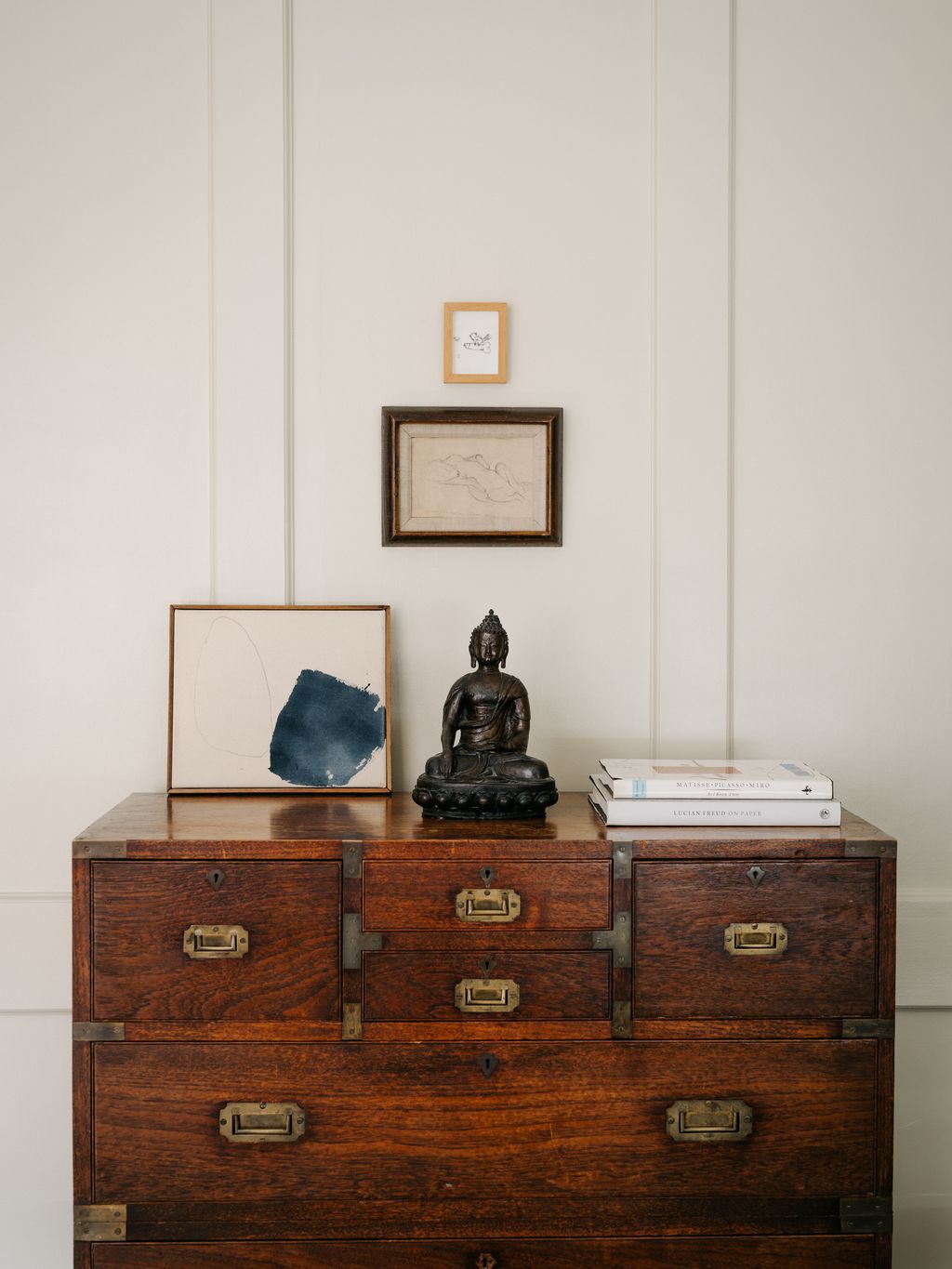 A 19thcentury Buddha stands on an early 19thcentury teak campaign chest of drawers with assortednbspworks of art...