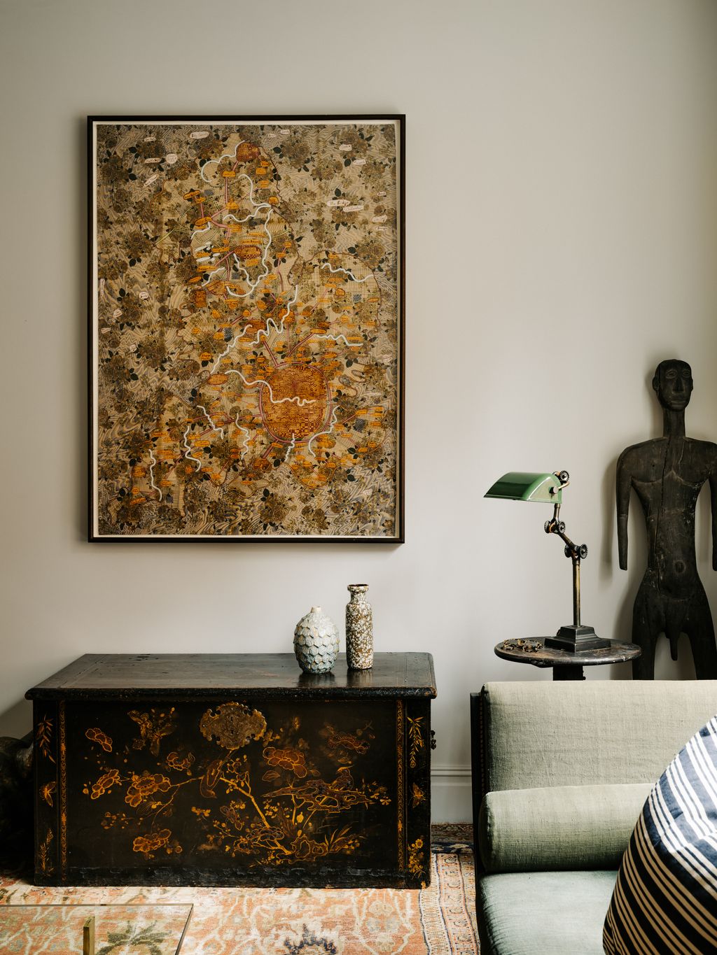 A textile by Grayson Perry hangs above a 17thcentury chinoiserie chest a tribal ebony figure stands in the corner.