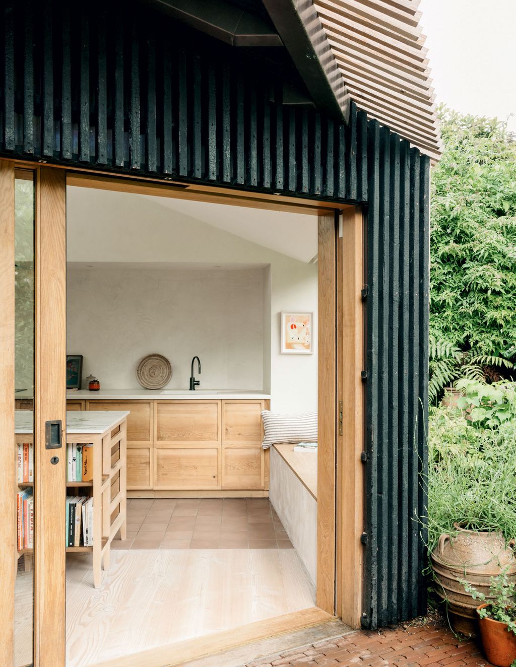 The mix of charred and uncharred larch baton cladding on the outer copper coat contrasts with the pale kitchen.