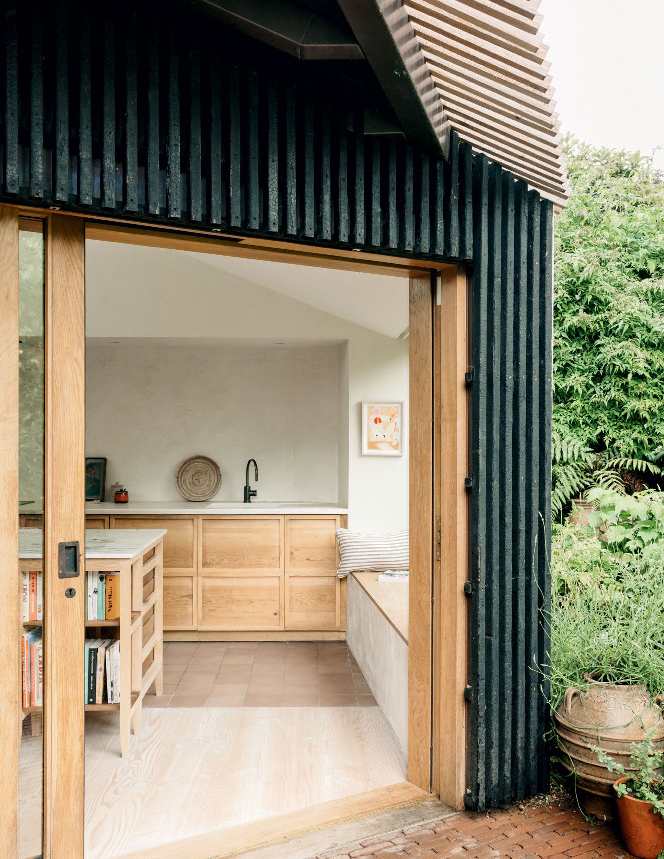 The mix of charred and uncharred larch baton cladding on the outer copper coat contrasts with the pale kitchen