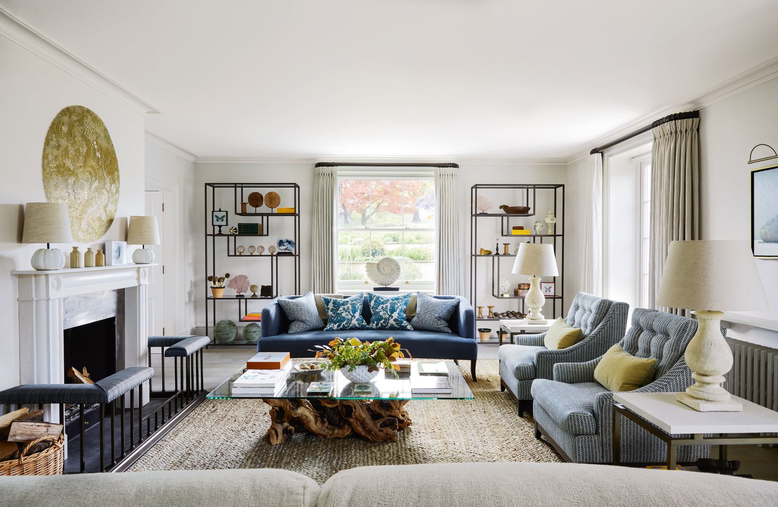 Bespoke metal shelf units from Tom Faulkner stand behind an Ensemblier ‘Eltham sofa in blue linen from Robert Allen with...
