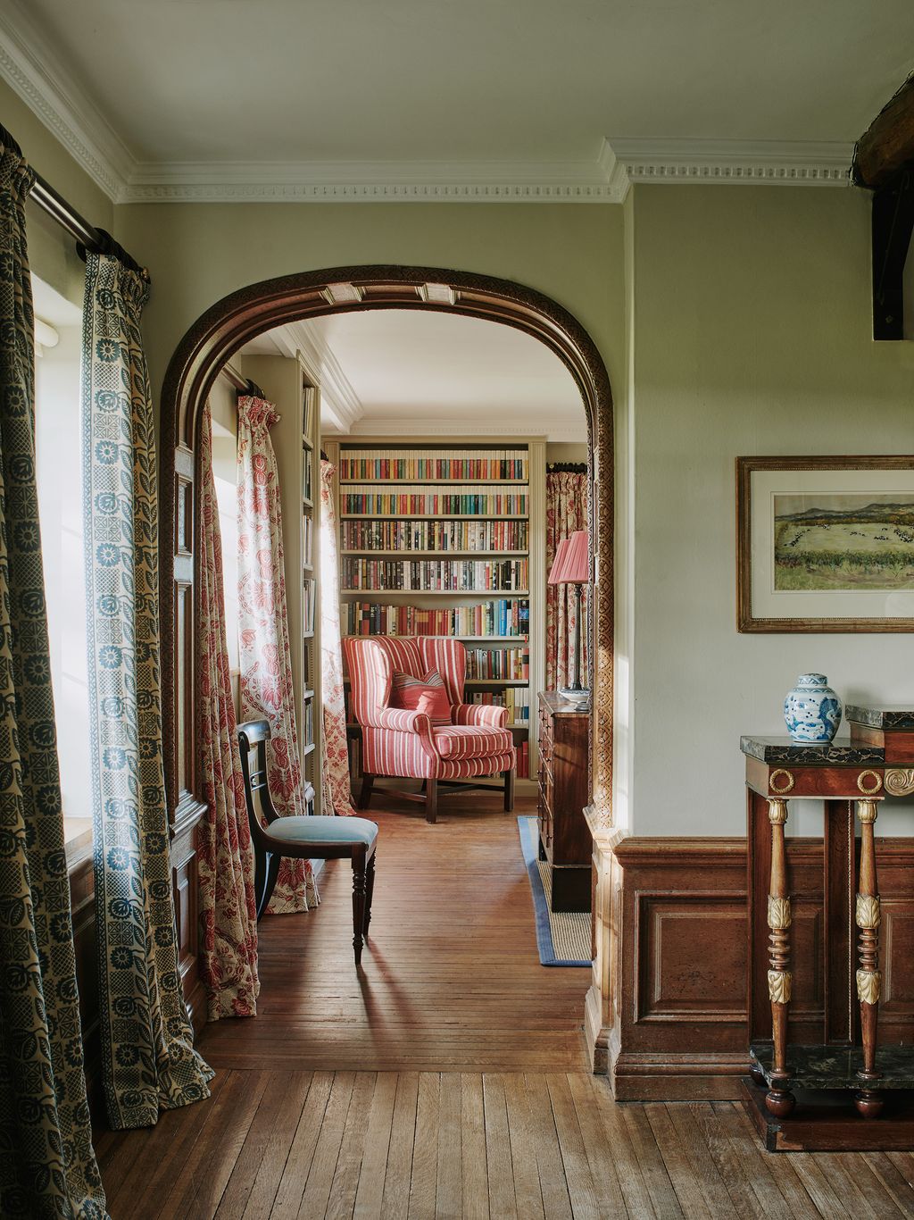 The arched doorway frames a chair covered in CC Milano's ‘Palea Rigato Cherry. Curtains in 'Bilibine Blue' from Dcors...