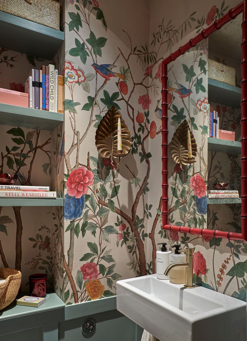 In the tiny downstairs loo a bold wallpaper from Gucci sits perfectly with the Robin Myerscough mirror and brass sconces...