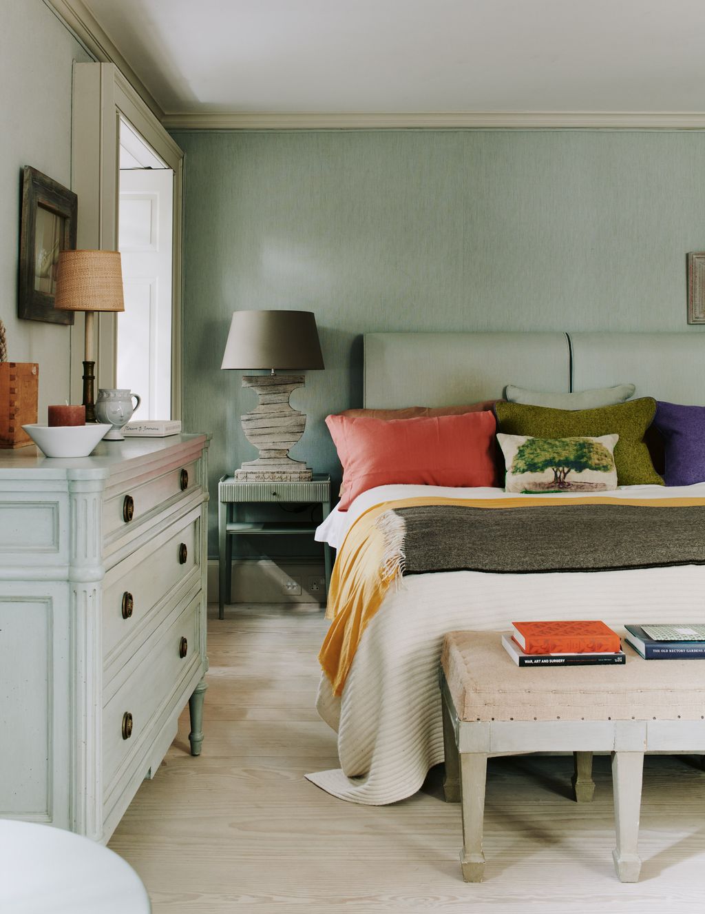 The walls in this bedroom are covered in an aqua linen which continues onto the headboard made by Jon Rhodes. The side...