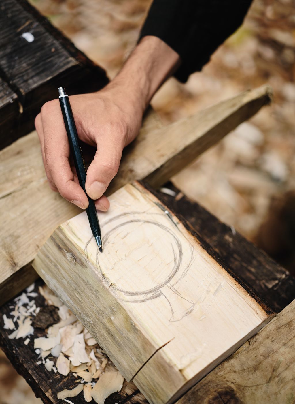 Sketching a 'Stork Wood Vessel' design onto wood.