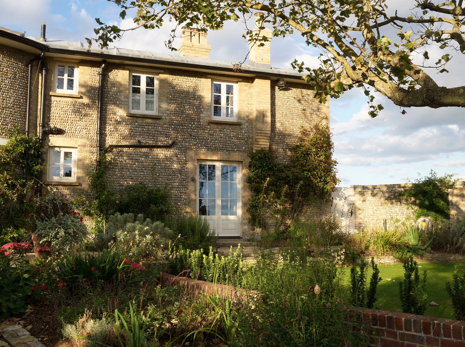 The Grade IIlisted brickandflint house is set within beautiful gardens designed by Xa Tollemache.