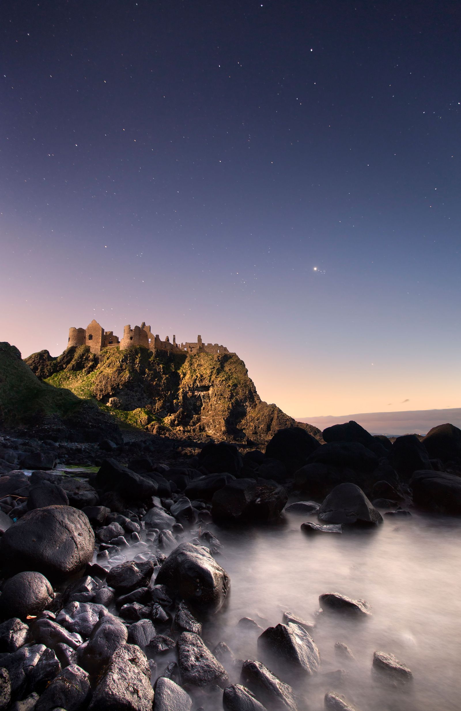 CY5MF8 Dunluce Castle captured at night under moonlight.