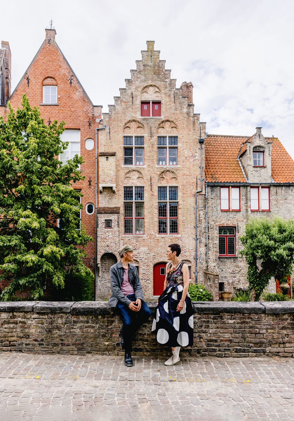 The couple beside the canal in the historic heart of Bruges the distinctive townhouse behind them dates back to 1530