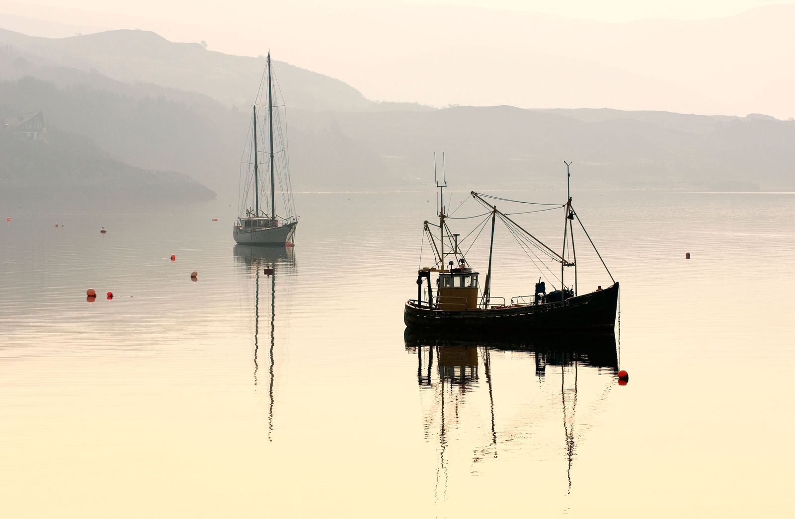 DE69JN Yacht and inshore fishing boat at anchor on Loch Broom at Ullapool Highland Region northwest Scotland UK. Dawn haze