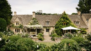 At the back of the Cotswoldstone house two seating areas one an old wooden pergola swathed in fragrant white Rosa...