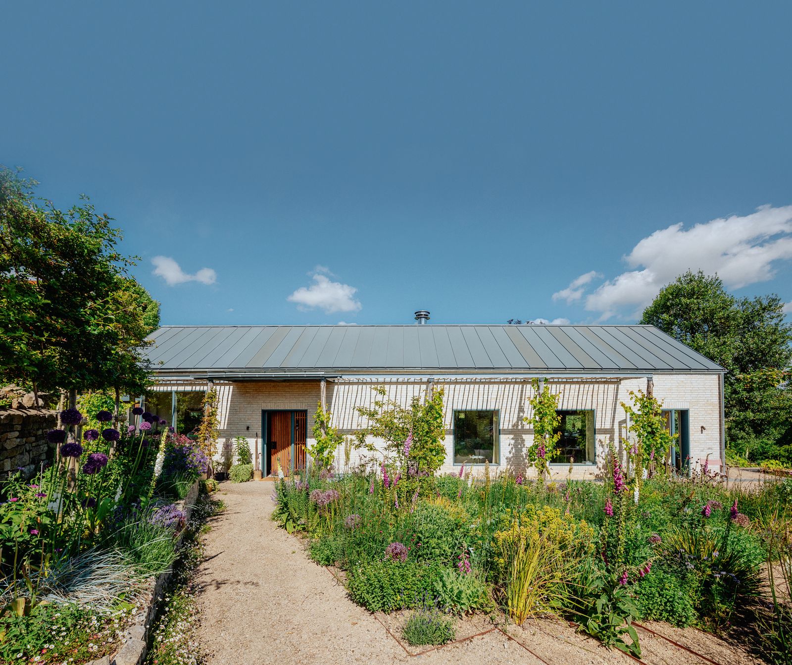 Walls in handmade creamcoloured bricks by Danish company Petersen Tegl are complemented by a zinc roof which reflects...
