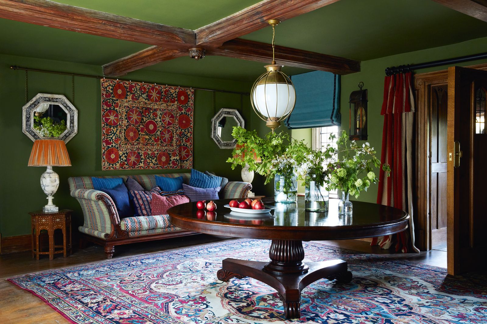 In the entrance hall Farrow amp Balls ‘Bancha on the walls and ceiling sets off the antique suzani wall hanging and the...