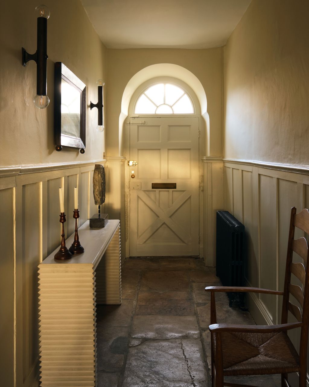 In the hall the wall lights were sourced from Matthew Cox. The armchair is 20th Century Neville Neal. The candlesticks...