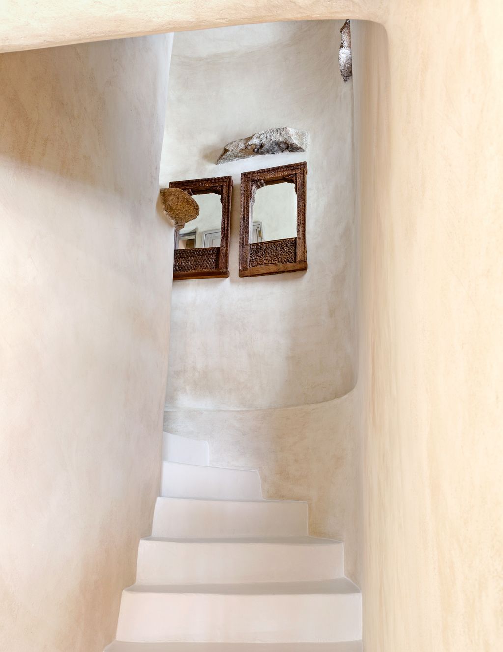 Wooden mirrors from Marrakech hang on the limedplaster wall of the staircase up to the main bedroom.