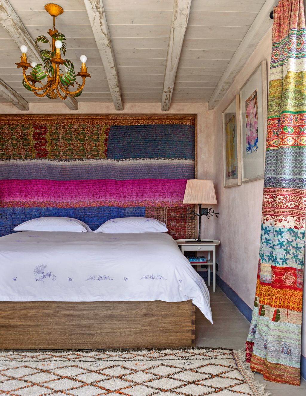 In the main bedroom Indian textiles were used for the headboard and curtains the toleware palm tree chandelier is a...