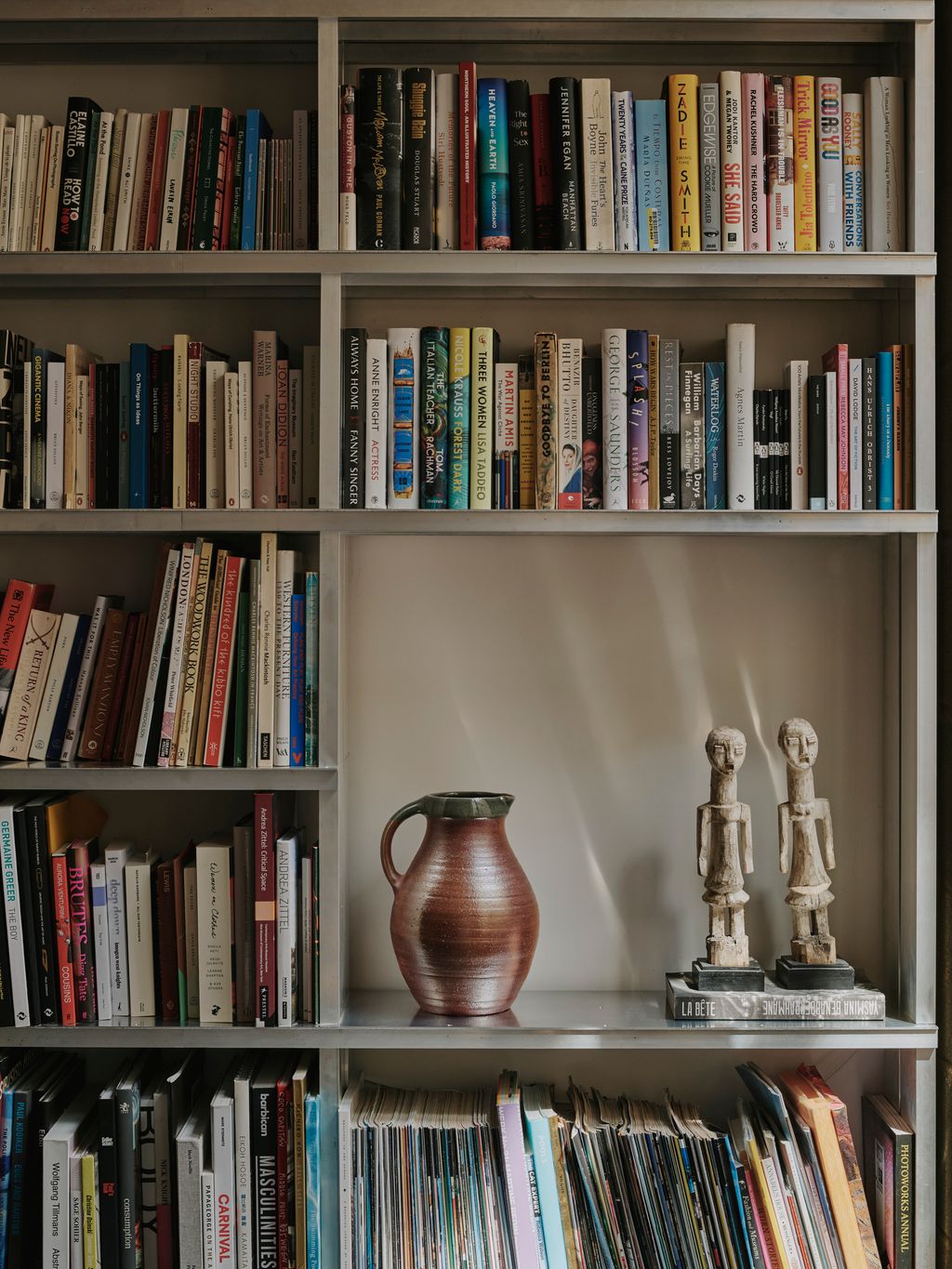 The bookshelf also displays a jug by Darren Ellis and antique sculptures bought by Shaw's partner.