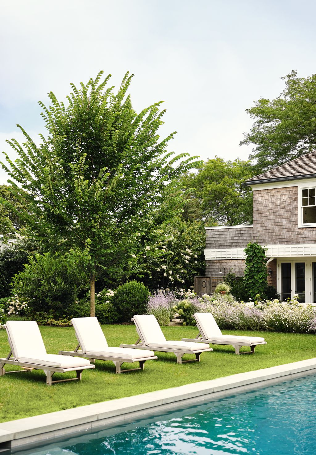 Flowing borders of herbaceous perennials edge the lawn that surrounds the pool creating a soft beautiful backdrop